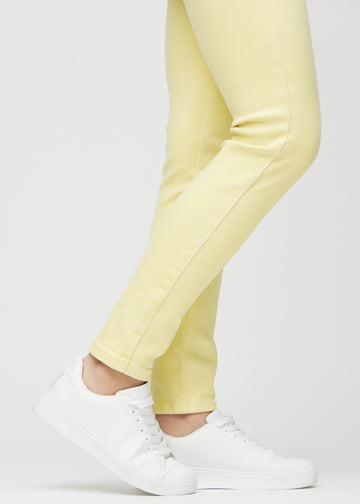 Slimjeans för kvinnor i ljusgul, färgen Lemonades. Närbild vid anklarna på en modell som visar passformen vid bensluten.