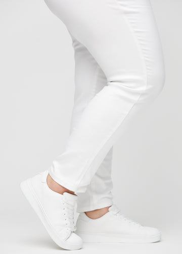 Slimjeans för kvinnor i vit, färgen Marguerites. Närbild vid anklarna på en plus size-modell som visar passformen vid bensluten.