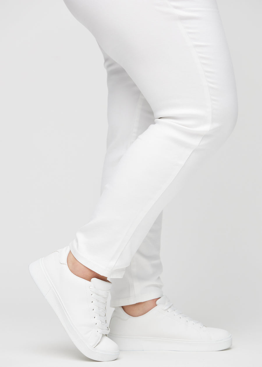 Slimjeans för kvinnor i vit, färgen Marguerites. Närbild vid anklarna på en plus size-modell som visar passformen vid bensluten.