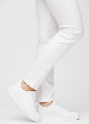 Slimjeans för kvinnor i vit, färgen Marguerites. Närbild vid anklarna på en modell som visar passformen vid bensluten.