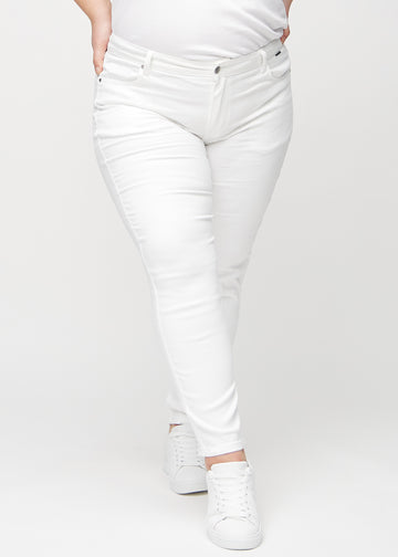 Slimjeans för kvinnor i vit, färgen Marguerites. Framifrån på en plus size-modell, med kroppsnära ben och lite mer utrymme vid anklarna.