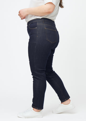 Djupt mörkblå denim jeans för kvinnor i färgen Midnights med slim passform sedd från sidan på plus-size-modell.