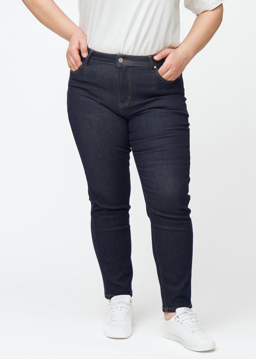 Djupt mörkblå denim jeans för kvinnor i färgen Midnights med slim passform sedd framifrån på plus-size-modell.