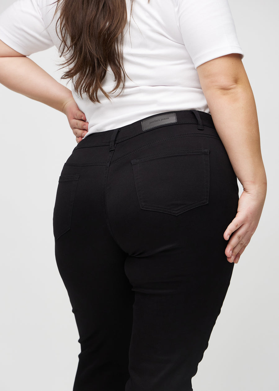Slimjeans för kvinnor i svart, färgen Ravens. Närbild bakifrån på en plus size-modell som visar detaljerna.