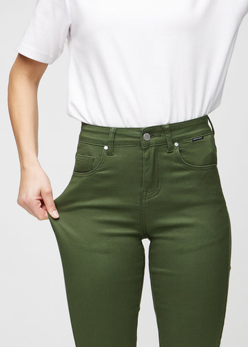 Slimjeans för kvinnor i mörkgrön, färgen Renewals. En modell drar i jeanstyget vid låret för att visa stretchen.