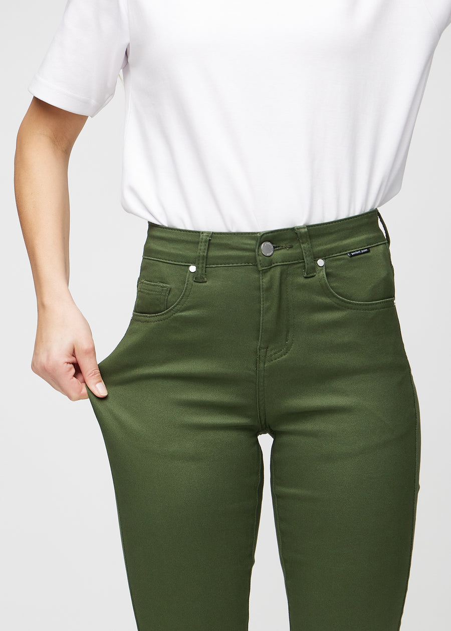 Slimjeans för kvinnor i mörkgrön, färgen Renewals. En modell drar i jeanstyget vid låret för att visa stretchen.
