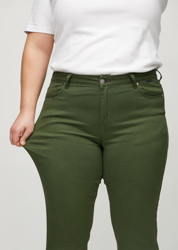 Slimjeans för kvinnor i mörkgrön, färgen Renewals. En plus size-modell drar i jeanstyget vid låret för att visa stretchen.
