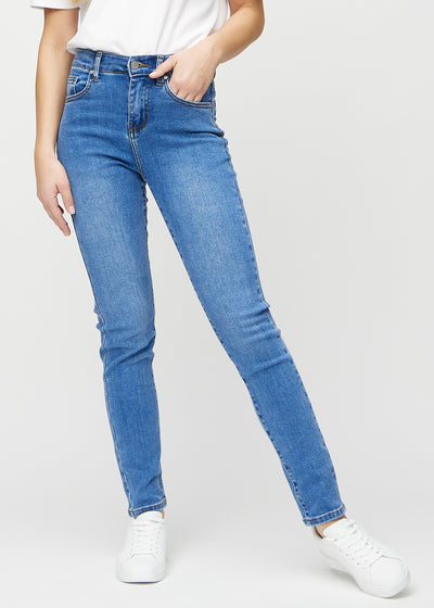 Slimjeans för kvinnor i blå, färgen Rivers. Framifrån på en modell, med kroppsnära ben och lite mer utrymme vid anklarna.