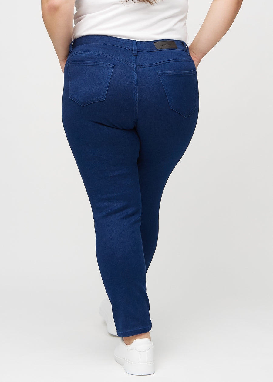 Slimjeans för kvinnor i mörkblå, färgen Royals. Bakifrån på en plus size-modell, så att hela passformen syns.