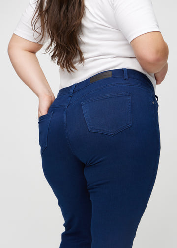 Slimjeans för kvinnor i mörkblå, färgen Royals. Närbild bakifrån på en plus size-modell som visar detaljerna.
