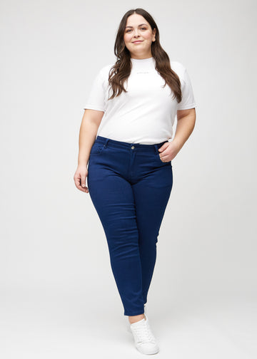 Slimjeans för kvinnor i mörkblå, färgen Royals. Helbild av en plus size-modell som bär jeansen.