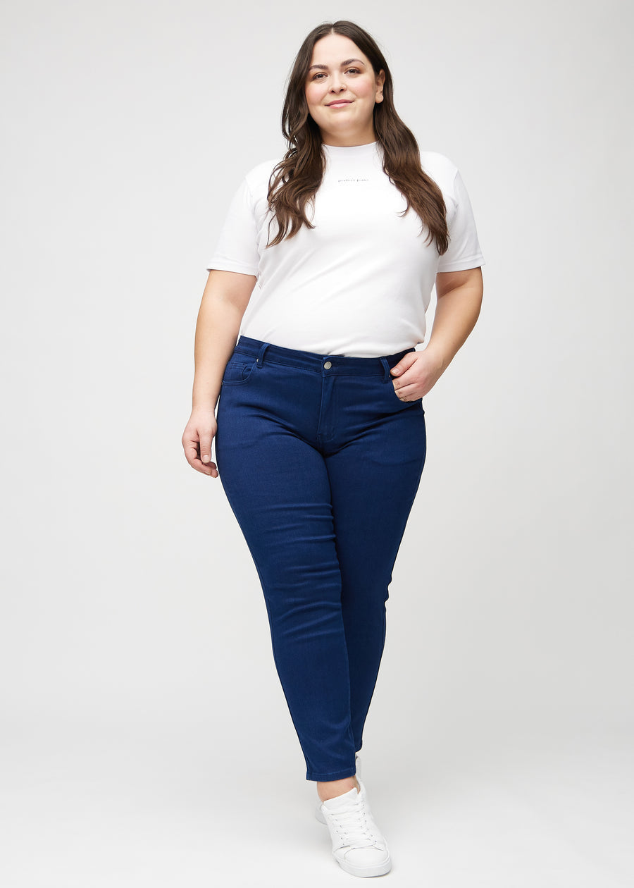 Slimjeans för kvinnor i mörkblå, färgen Royals. Helbild av en plus size-modell som bär jeansen.