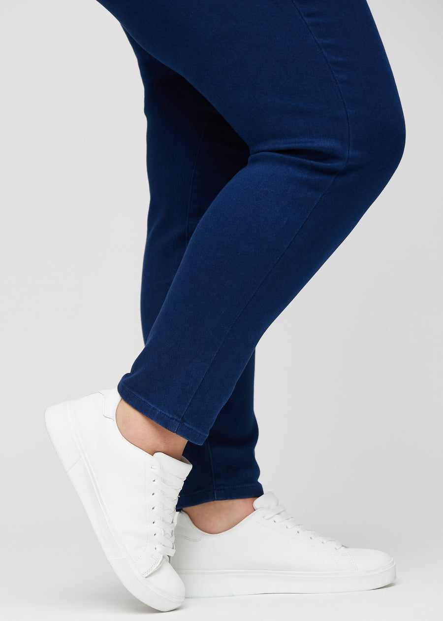 Slimjeans för kvinnor i mörkblå, färgen Royals. Närbild vid anklarna på en plus size-modell som visar passformen vid bensluten.