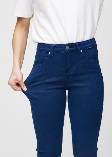Slimjeans för kvinnor i mörkblå, färgen Royals. En modell drar i jeanstyget vid låret för att visa stretchen.