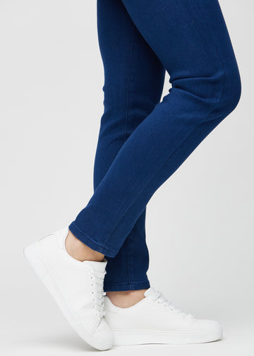 Slimjeans för kvinnor i mörkblå, färgen Royals. Närbild vid anklarna på en modell som visar passformen vid bensluten.