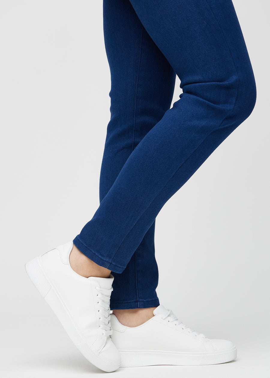 Slimjeans för kvinnor i mörkblå, färgen Royals. Närbild vid anklarna på en modell som visar passformen vid bensluten.