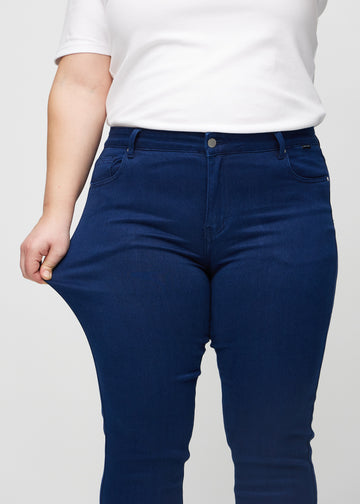 Slimjeans för kvinnor i mörkblå, färgen Royals. En plus size-modell drar i jeanstyget vid låret för att visa stretchen.