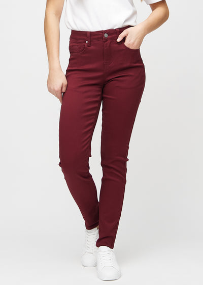 Slimjeans för kvinnor i mörkröd, färgen Santas. Framifrån på en modell, med kroppsnära ben och lite mer utrymme vid anklarna.