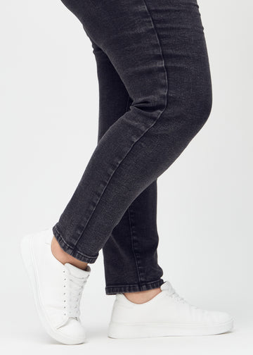 Slimjeans för kvinnor i mörkgrå, färgen Shadows. Närbild vid anklarna på en plus size-modell som visar passformen vid bensluten.