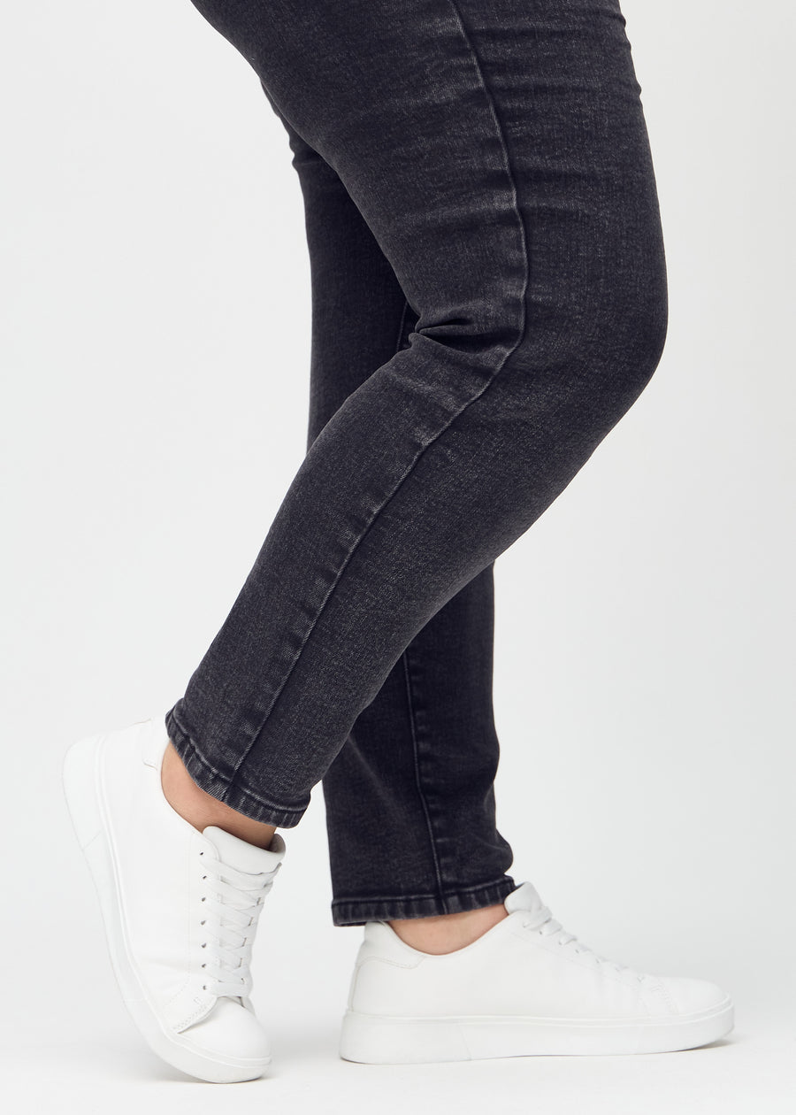 Slimjeans för kvinnor i mörkgrå, färgen Shadows. Närbild vid anklarna på en plus size-modell som visar passformen vid bensluten.