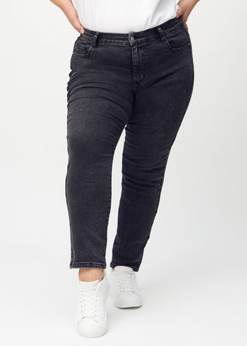 Slimjeans för kvinnor i mörkgrå, färgen Shadows. Framifrån på en plus size-modell, med kroppsnära ben och lite mer utrymme vid anklarna.