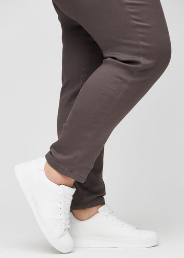 Slimjeans för kvinnor i gråbrun, färgen Thunders. Närbild vid anklarna på en plus size-modell som visar passformen vid bensluten.