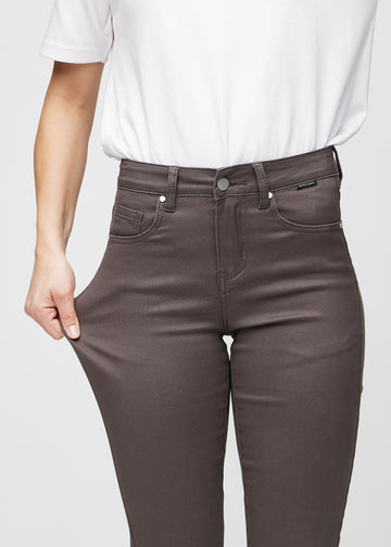 Slimjeans för kvinnor i gråbrun, färgen Thunders. En modell drar i jeanstyget vid låret för att visa stretchen.