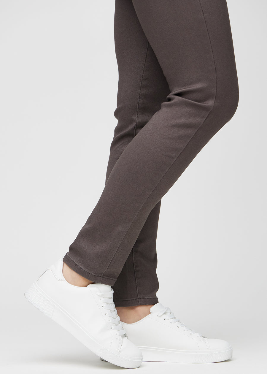 Slimjeans för kvinnor i gråbrun, färgen Thunders. Närbild vid anklarna på en modell som visar passformen vid bensluten.