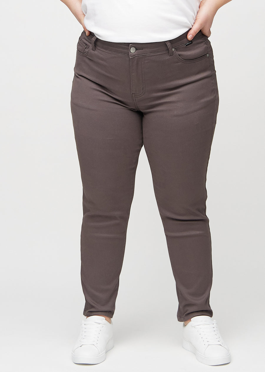 Slimjeans för kvinnor i gråbrun, färgen Thunders. Framifrån på en plus size-modell, med kroppsnära ben och lite mer utrymme vid anklarna.