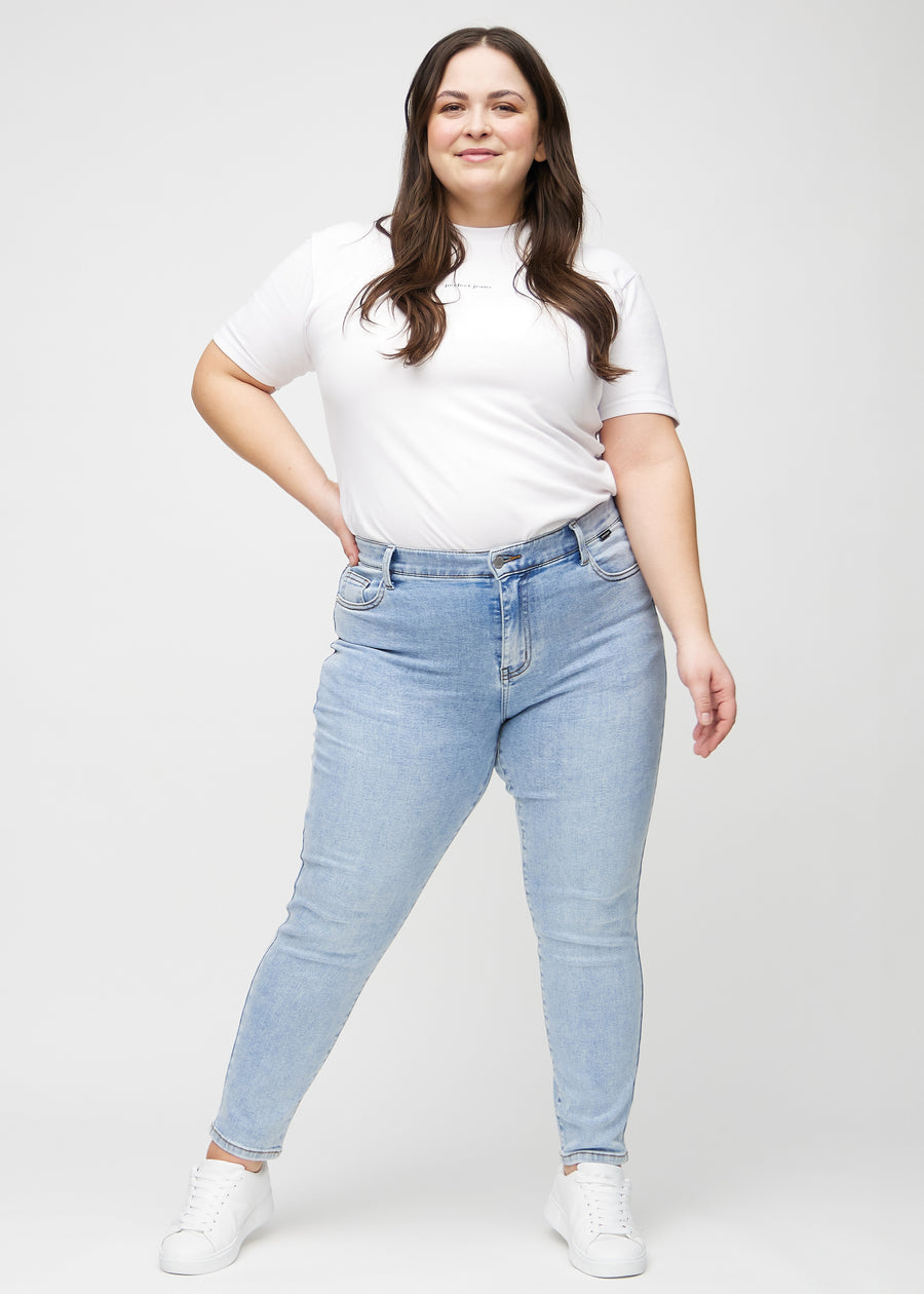 Slimjeans för kvinnor i ljusblå, färgen Waves. Helbild av en plus size-modell som bär jeansen.
