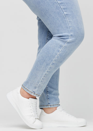 Slimjeans för kvinnor i ljusblå, färgen Waves. Närbild vid anklarna på en plus size-modell som visar passformen vid bensluten.