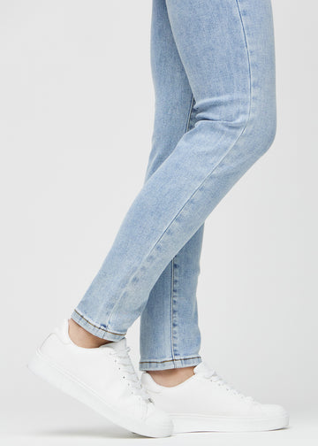 Slimjeans för kvinnor i ljusblå, färgen Waves. Närbild vid anklarna på en modell som visar passformen vid bensluten.