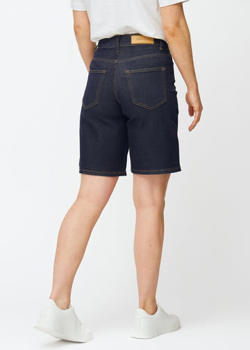 Mörkblå denimshorts för dam i färgen Midnights sett bakifrån, där längden strax över knät syns.