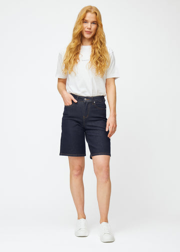 Helbild av modell i mörkblå denimshorts för dam i färgen Midnights med loose passform.