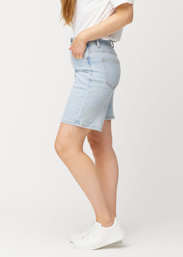 Modell sedd från sidan i ljusblå Waves denimshorts för kvinnor med medelhög midja (Mid Rise) och loose fit.