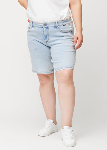 Kvinnlig modell sedd framifrån i ljusblå Waves denimshorts med medelhög midja (Mid Rise) och loose fit.