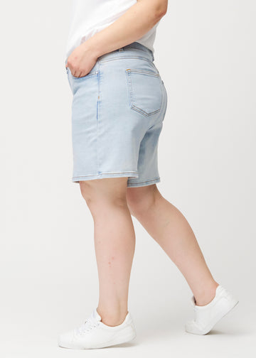 Kvinnlig modell sedd från sidan i ljusblå Waves denimshorts med medelhög midja (Mid Rise) och loose fit.