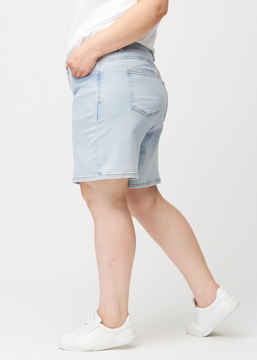 Kvinnlig modell sedd från sidan i ljusblå Waves denimshorts med medelhög midja (Mid Rise) och loose fit.
