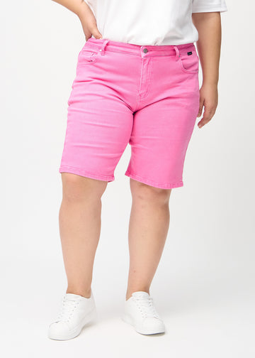 Ljusrosa regular middle shorts, modellnamn Flamingos, som går rakt ner längs benet och slutar precis ovanför knät på en plus-size-modell, sedda framifrån.