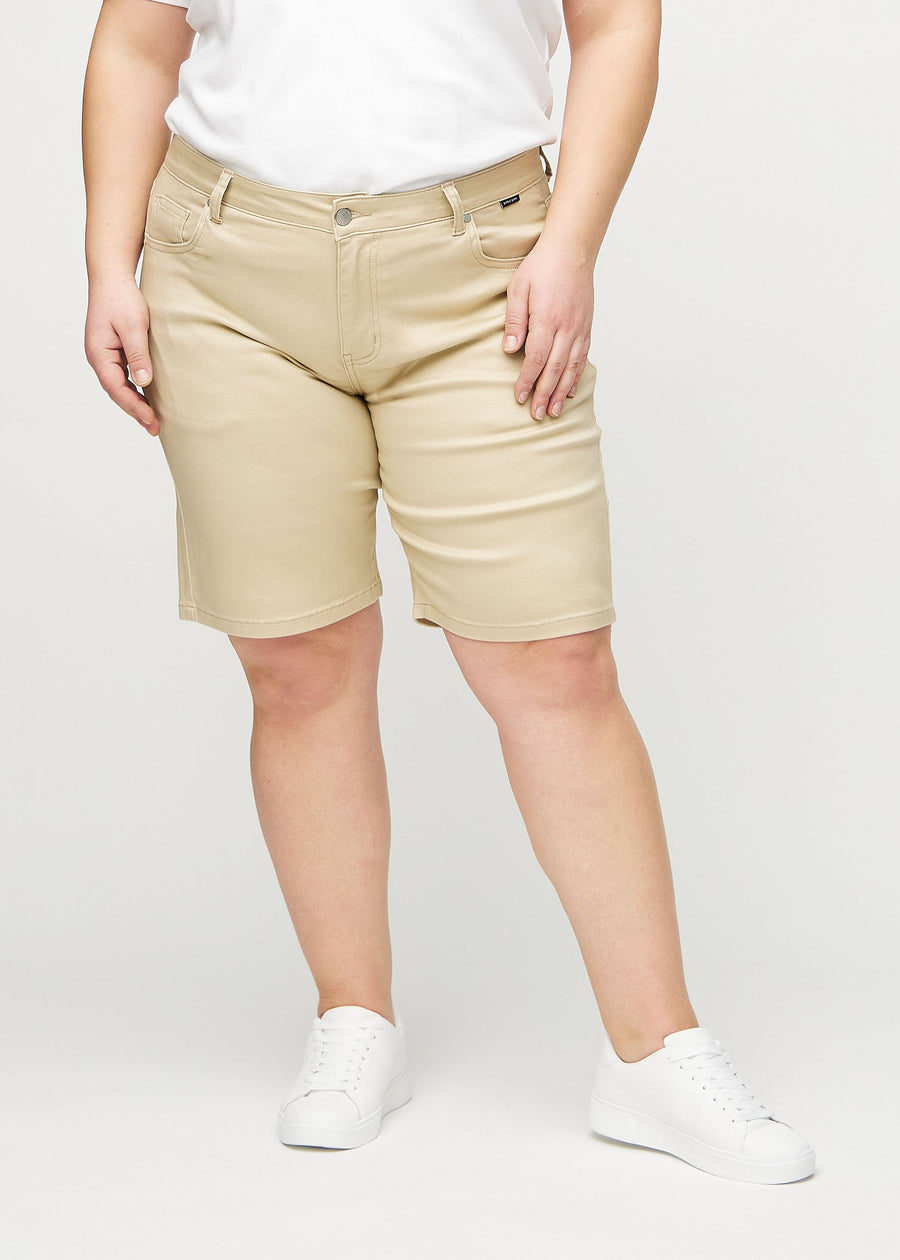 Beige regular middle shorts, modellnamn Gazelles, som går rakt ner längs benet och slutar precis ovanför knät på en plus-size-modell, sedda framifrån.