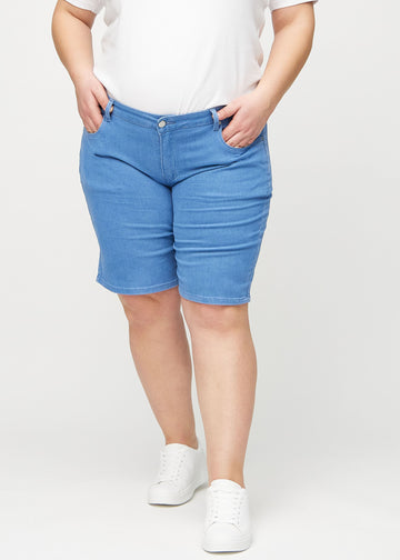 Blå regular middle shorts, modellnamn Geraniums, som går rakt ner längs benet och slutar precis ovanför knät på en plus-size-modell, sedd framifrån.