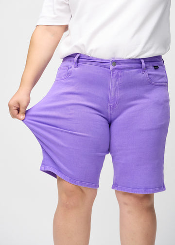 Plus-size-modellen sträcker ut shortsen vid låret för att visa stretch.