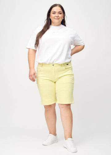 Helbild av en plus-size-modell i ljusgula regular middle shorts.