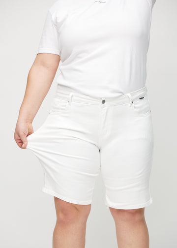 Plus size-modellen sträcker ut shortsen vid låret för att visa stretch.