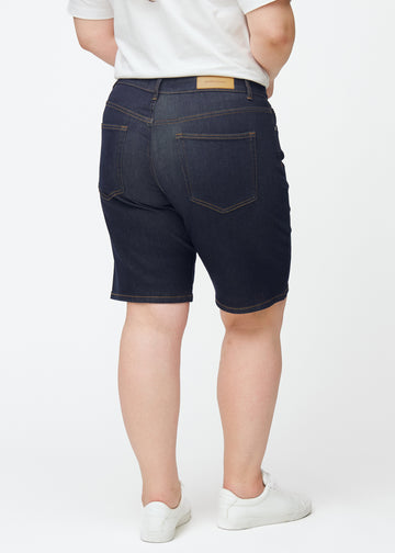 Mörkblå denimshorts för dam i färgen Midnights sett bakifrån på plus-size modell.