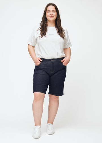 Helbild av plus-size modell i mörkblå denimshorts för dam i färgen Midnights med regular passform.