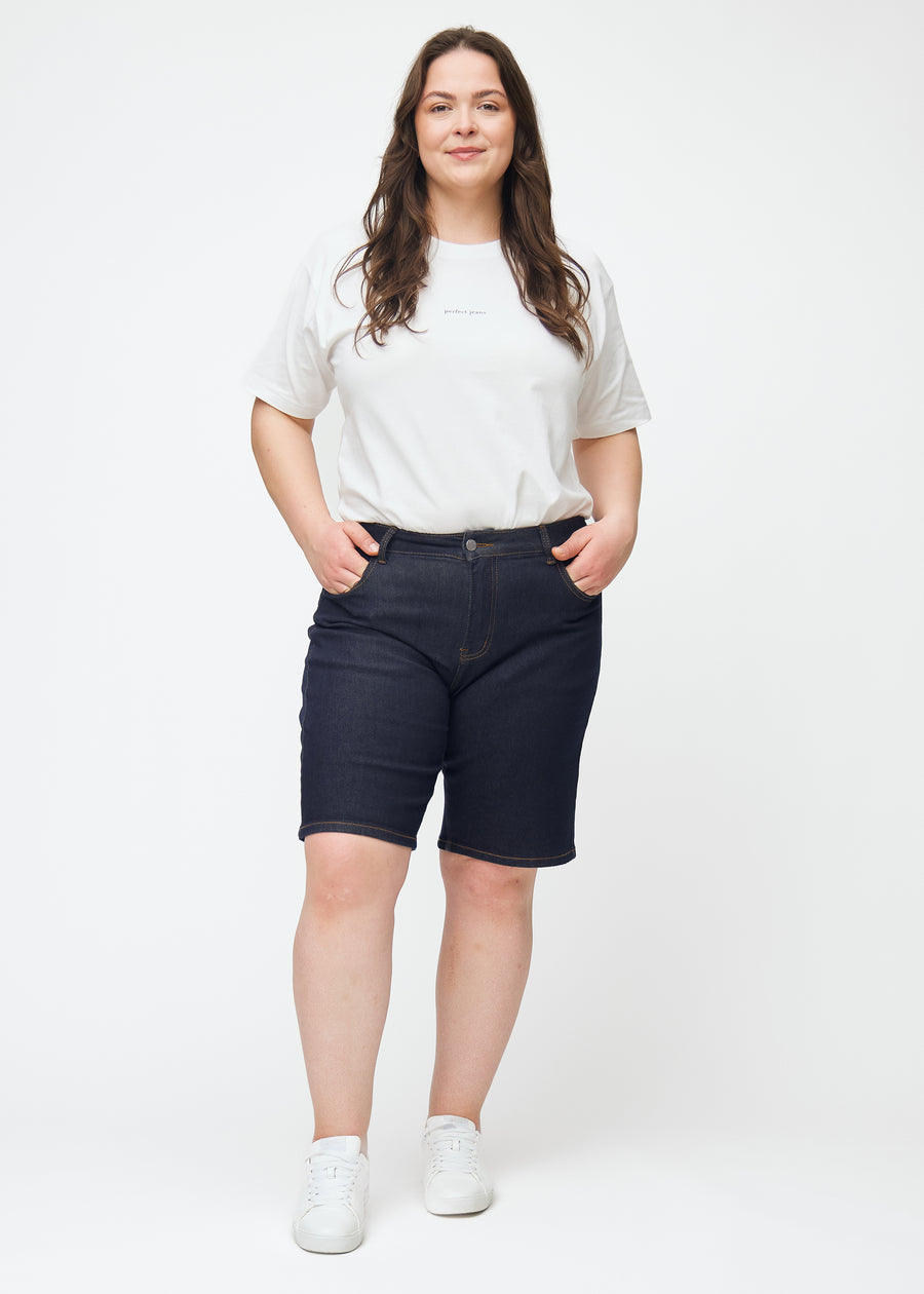 Helbild av plus-size modell i mörkblå denimshorts för dam i färgen Midnights med regular passform.