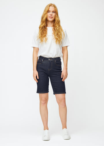 Helbild av modell i mörkblå denimshorts för dam i färgen Midnights med regular passform.