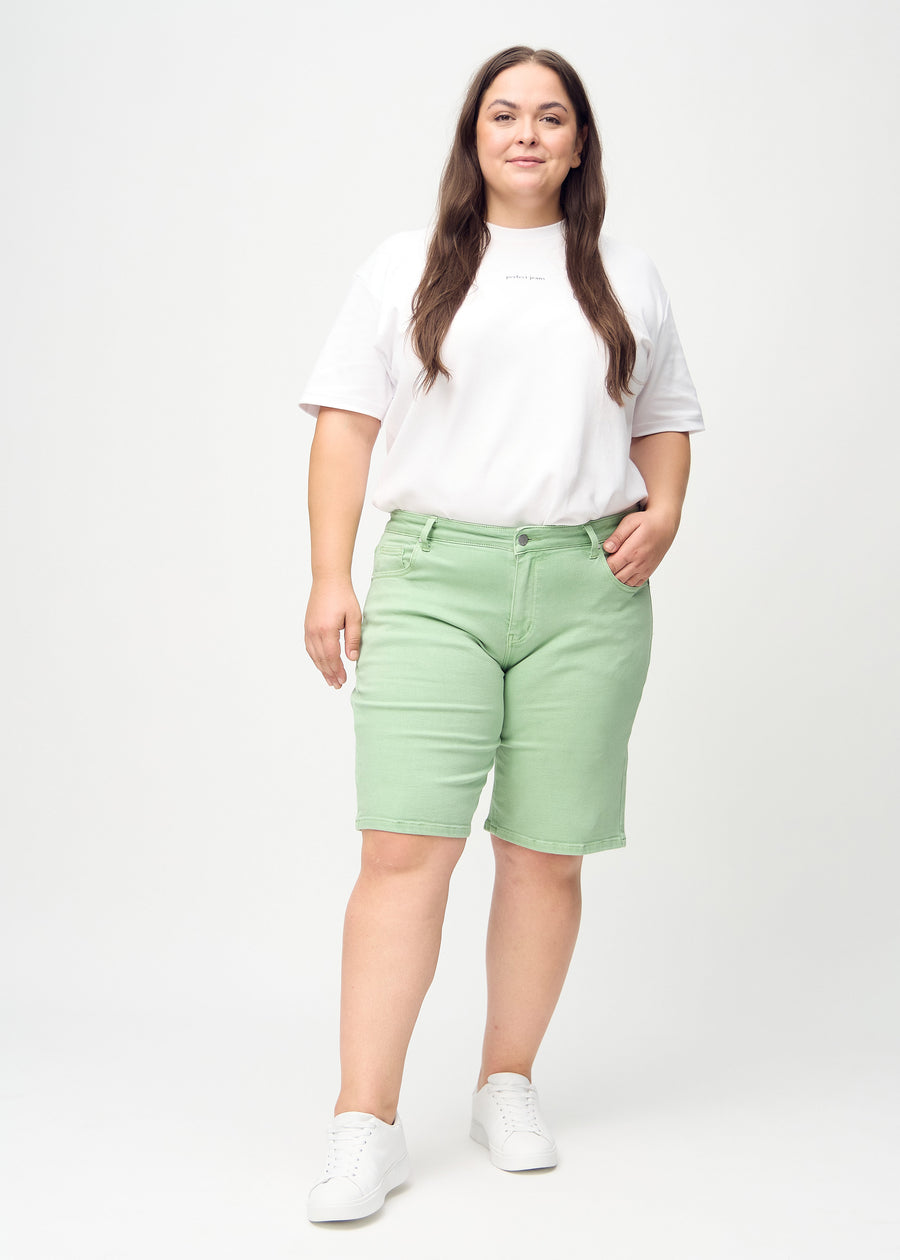 Helbild av en plus-size-modell i ljusgröna regular middle shorts.