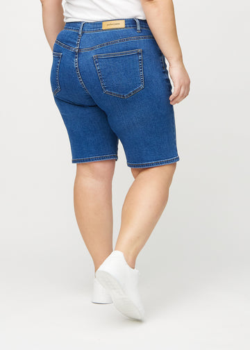 Mörk denim regular middle shorts sedd bakifrån på en plus-size-modell, så att man kan se hela produkten.